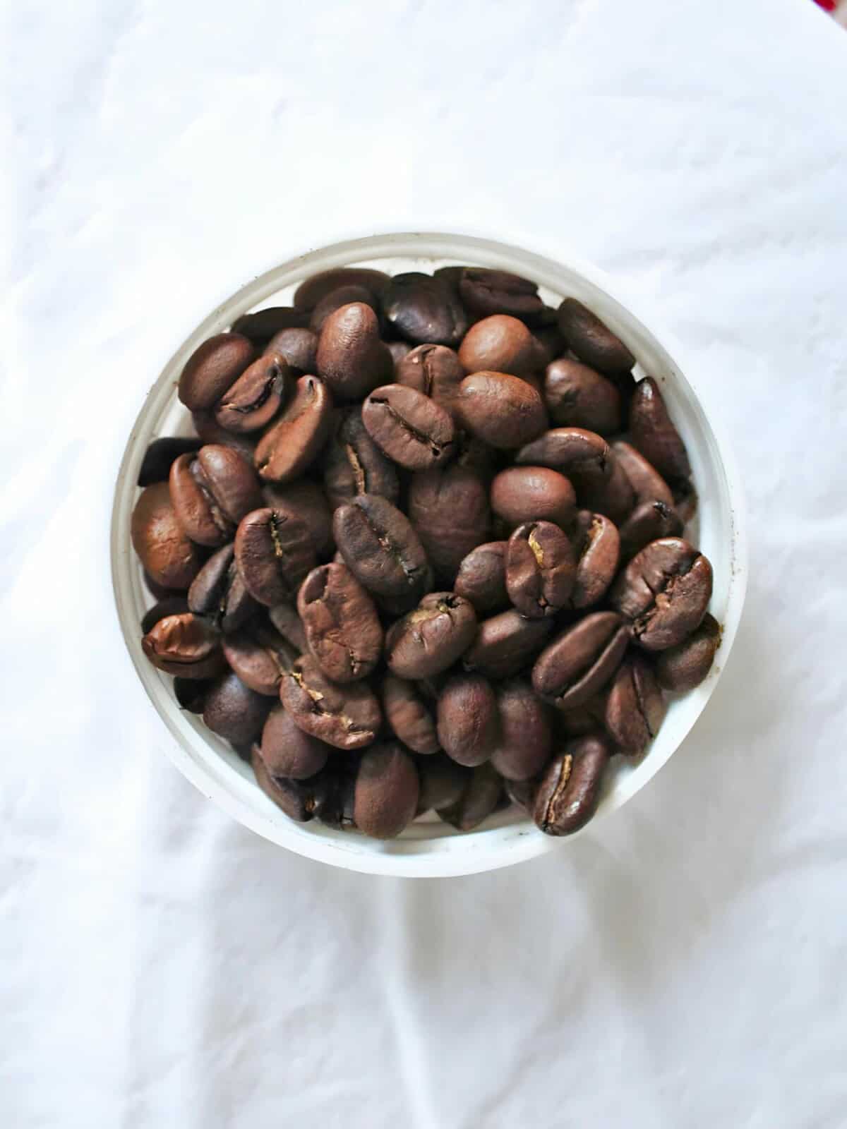 coffee beans in a bowl on a white cloth.