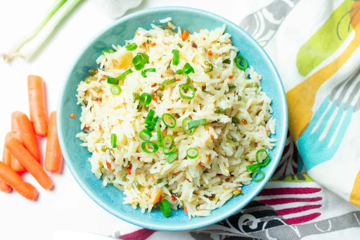 fried rice in a blue bowl with carrots and green onions.
