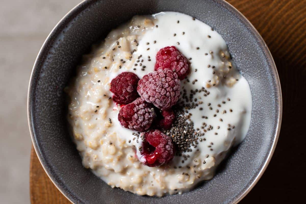 a bowl of porridge topped with raspberries and chia seeds.