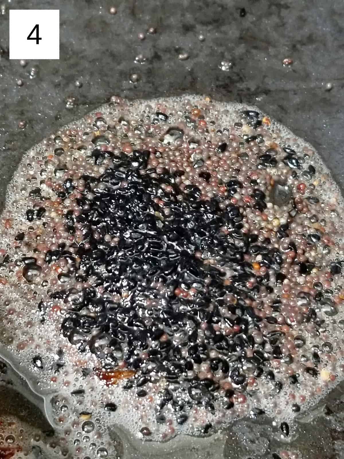 A mixture or nigella and mustard seeds in a pot.