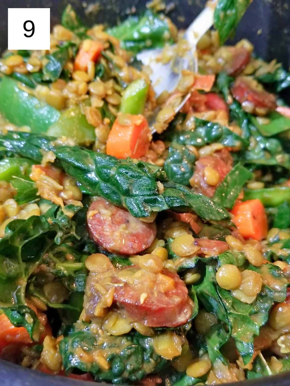 Cooked lentil stew with carrots, sweet potato, and kale in  a pot.