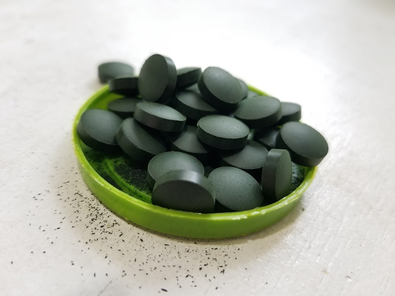 spirulina tablets in a green jar lid