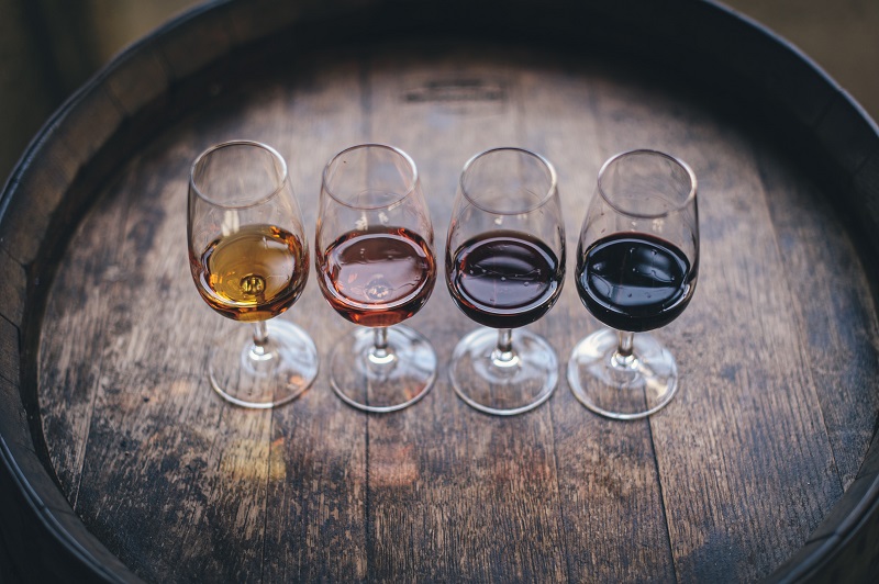 four glasses of wine on top of a wooden barrel.