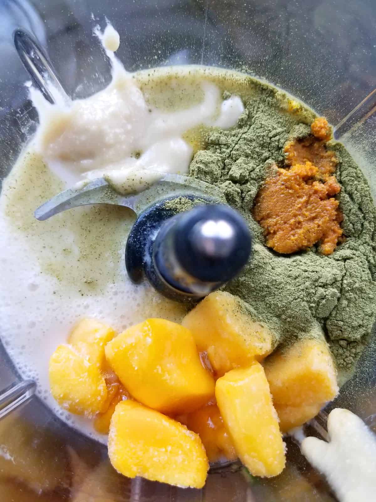 mango chunks, moringa powder, turmeric paste, coconut milk, macadamia nut butter, and other ingredients in a blender.