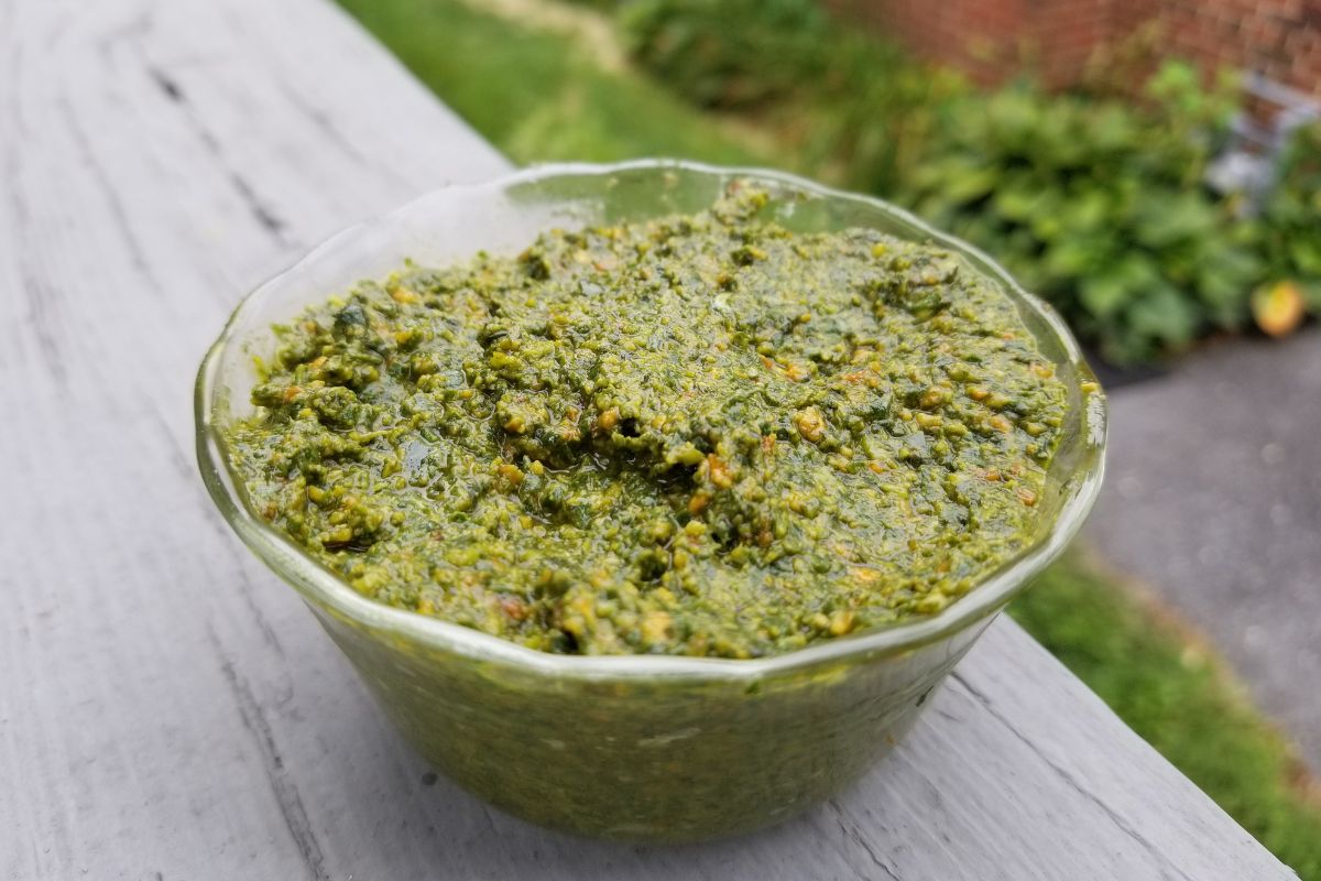 homemade pesto sauce in glass dish on a wooden background.