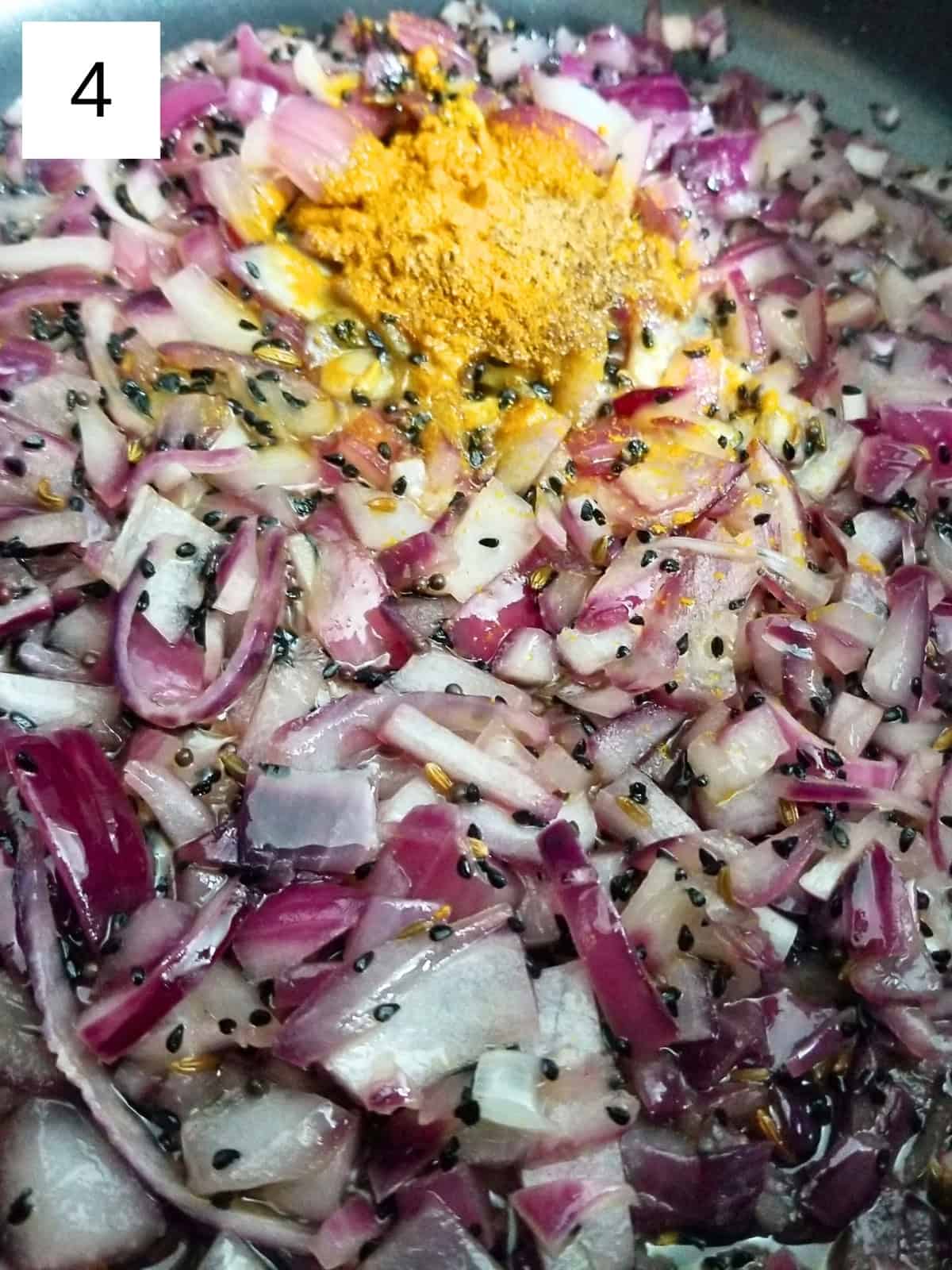 adding ground coriander and turmeric to a sautéed onion and seeds.
