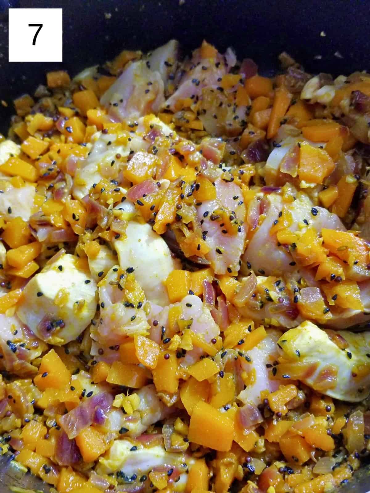 slices of chicken in a stirred butternut squash and seed mixture in a pan.