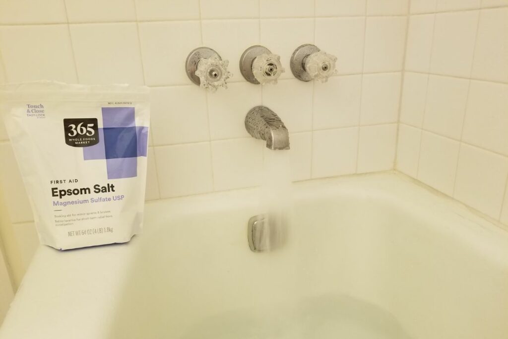 Epsom salt pack next to a bath tub being filled. 