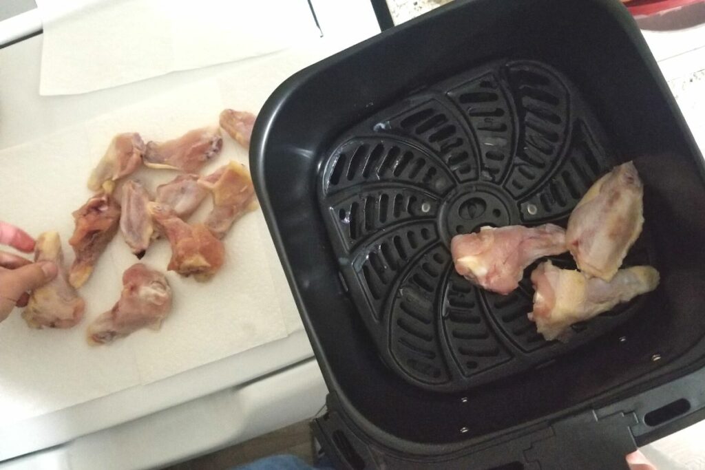 Raw chicken being cooked in an air fryer.