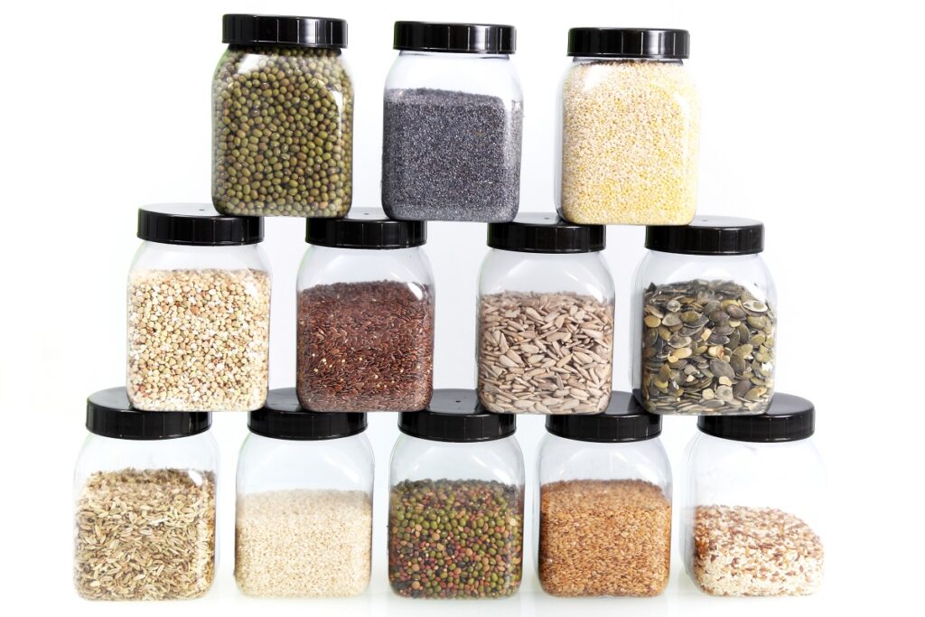 Stacked display of different kinds of edible seeds in a jar. 