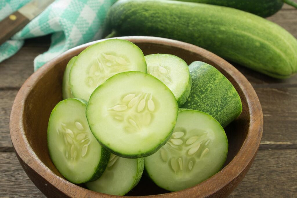 fresh cucumber slices neatly arranged in a rustic wooden bowl.