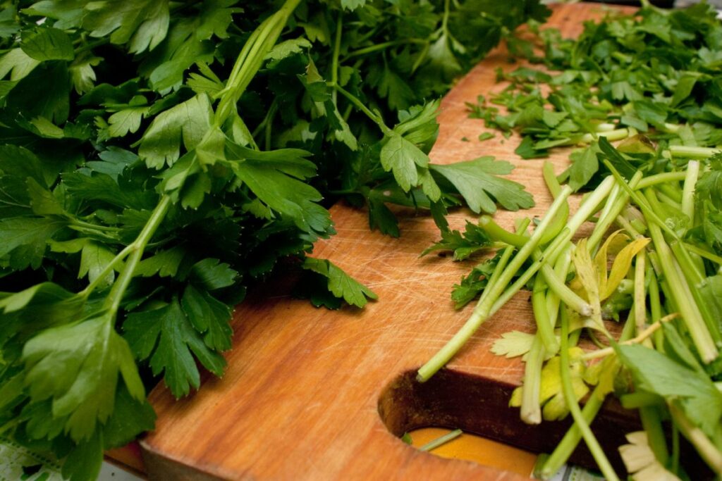 a cutting board with a bunch of parsley on it.