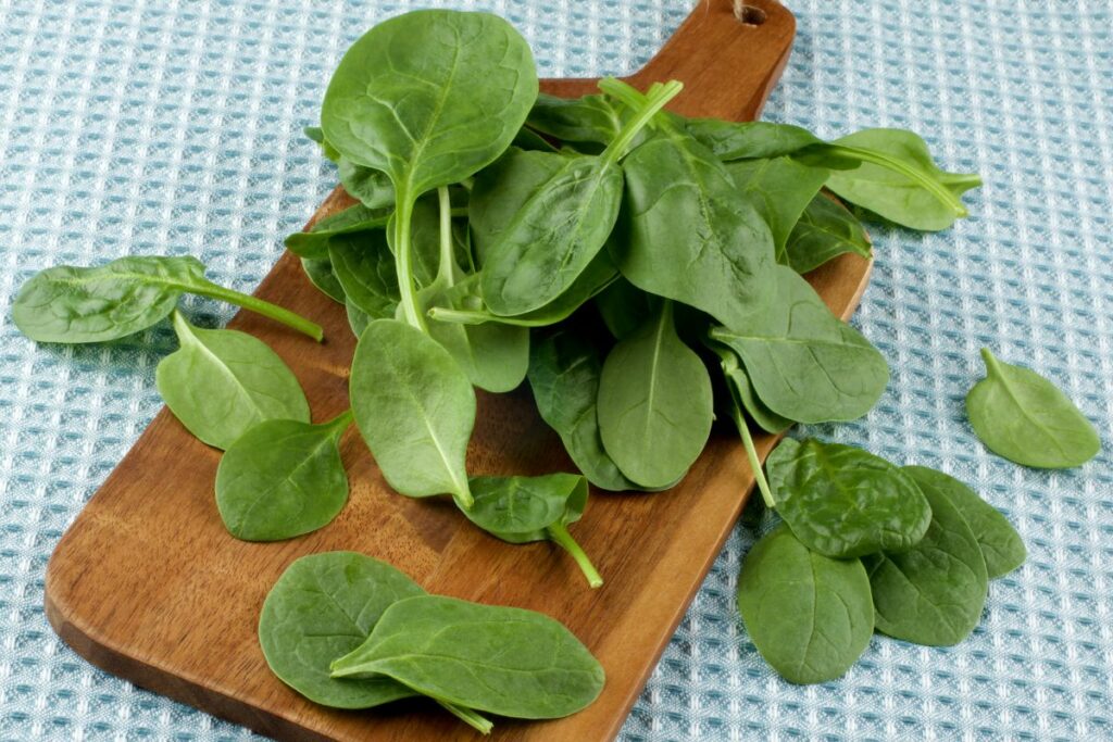 spinach leaves on a cutting board.
