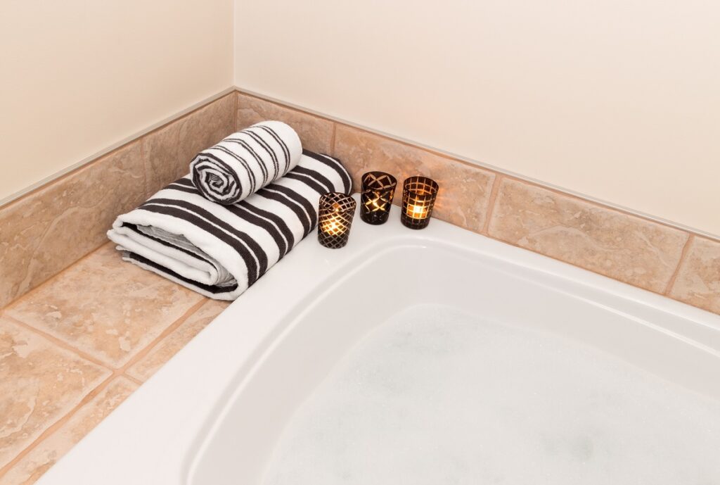 Towels and candles next to a bath tub.