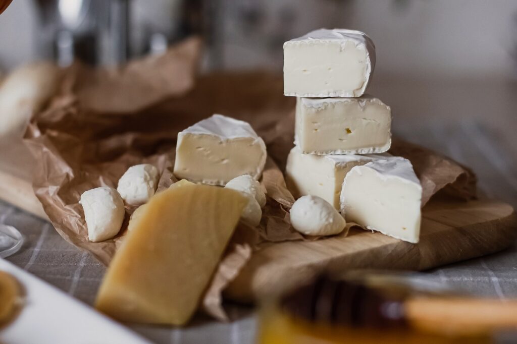 a selection of sliced cheeses on a wooden chopping board.