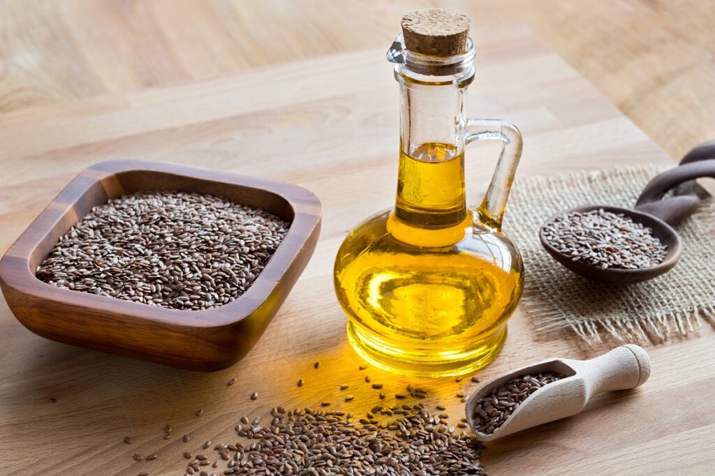 a bottle of flax seed oil, with flax seeds in the background.