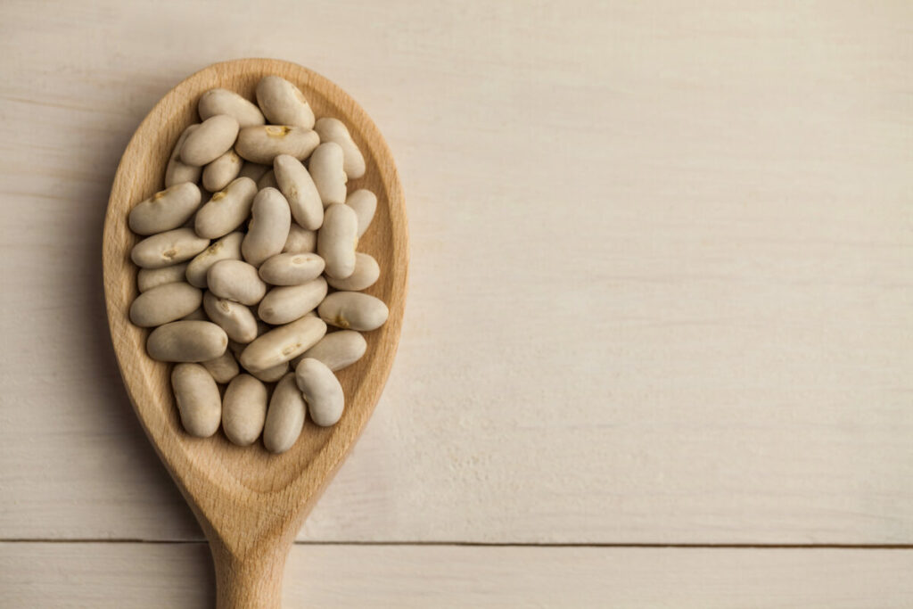 A serving of lima beans on a wooden spoon.