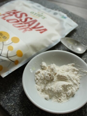 white bowl of cassava flour on a grey cutting board in front of a bag of Otto's cassava flour.