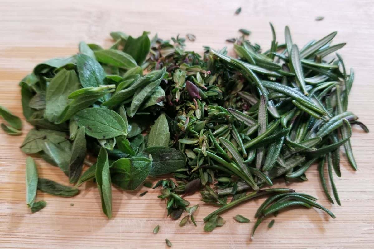 A mixture of chopped fresh herbs on a chopping board.