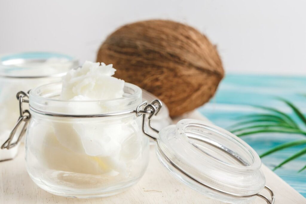 Coconut butter in a glass jar next to a coconut.