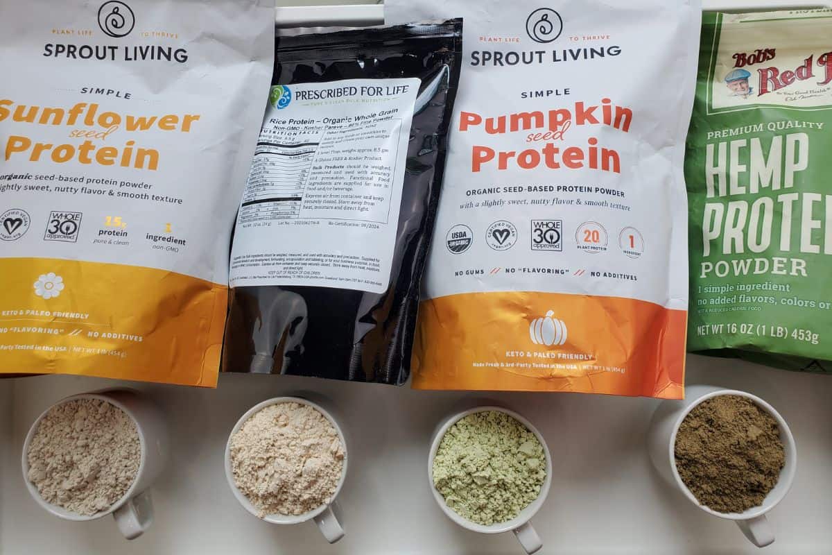 four different varieties of protein powder in pouches, with what was inside beneath in a white mug.