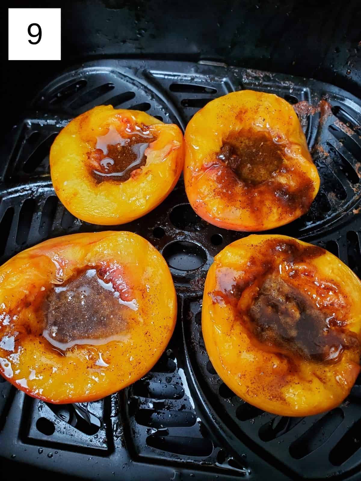four halves of peaches in an air fryer with spiced butter mixture
