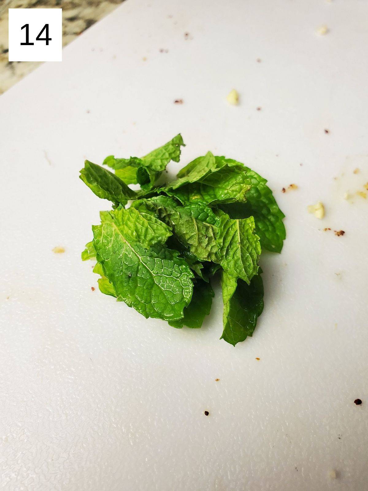 mint leaves on a white chopping board.