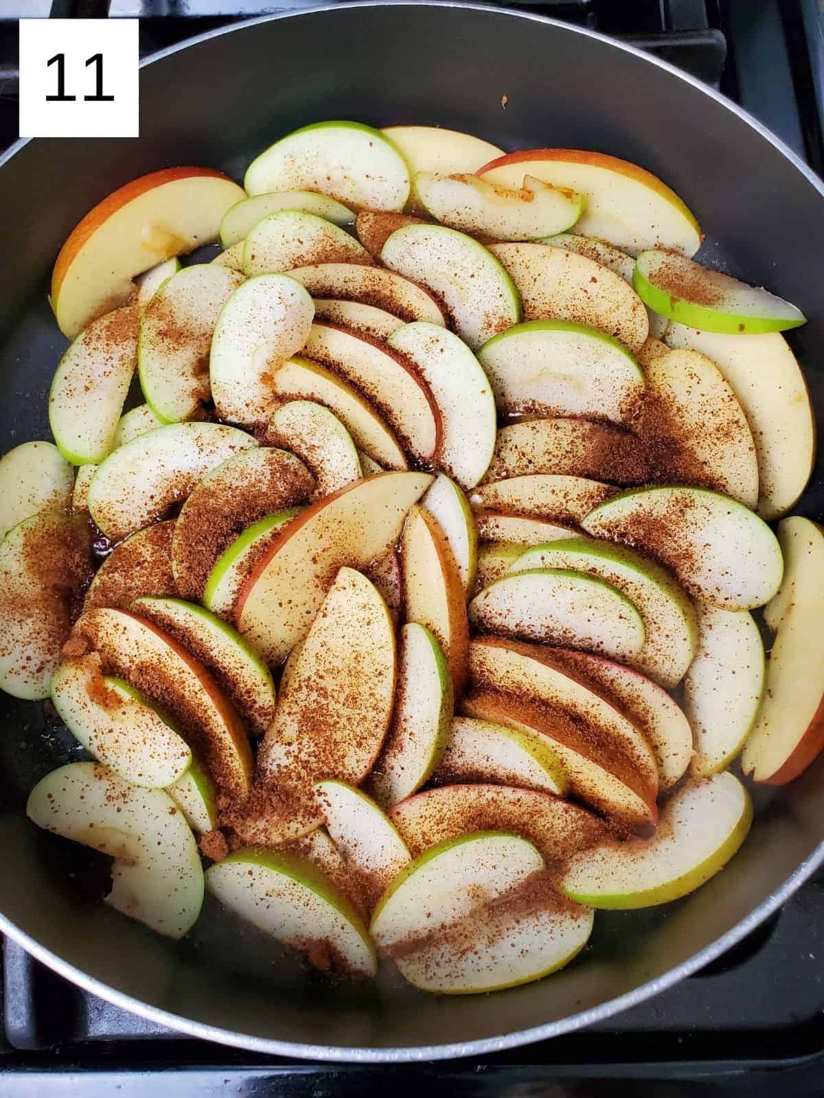 evenly cut slices of apples layered and seasoned with a sugar mixture in a pan.