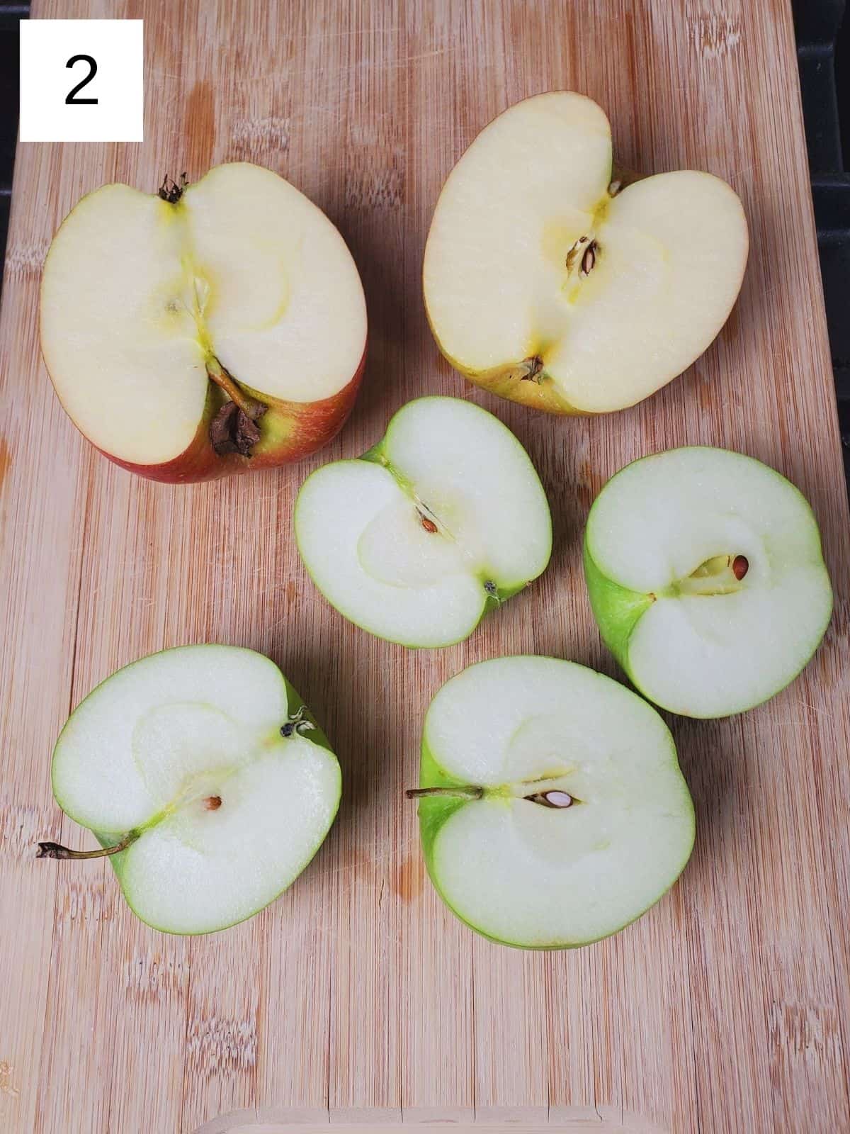 six halves of apples on a wooden cutting board.