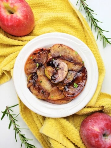 cooked caramelized apples on a white plate.