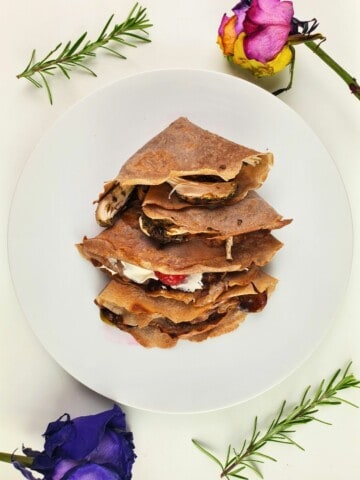 three pieces of chestnut flour crepes with different toppings and fillings on a plate.
