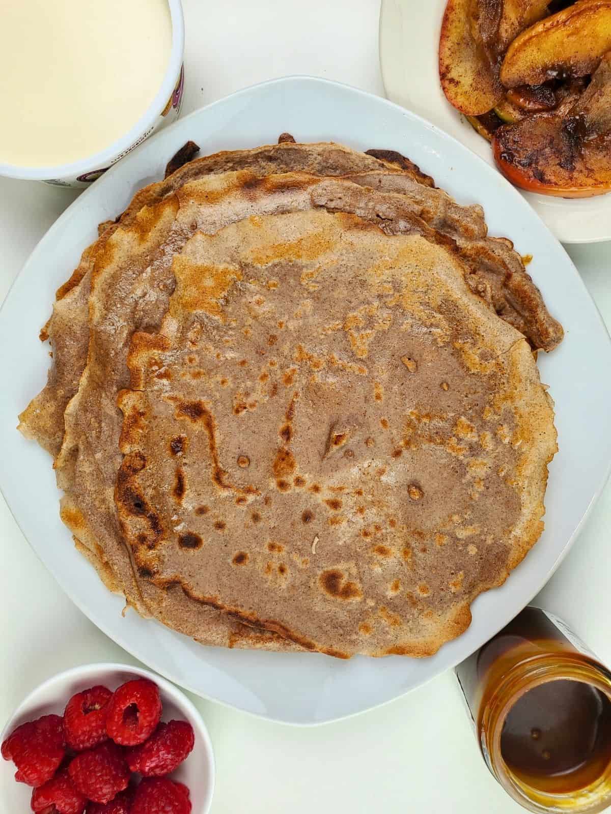 a well-cooked chestnut flour crepes on a plate, and various toppings and fillings to choose from.