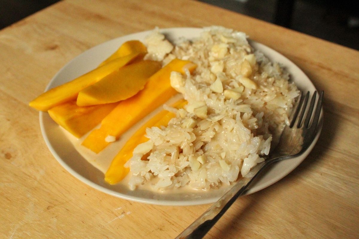 mango sticky rice with nuts on a plate.