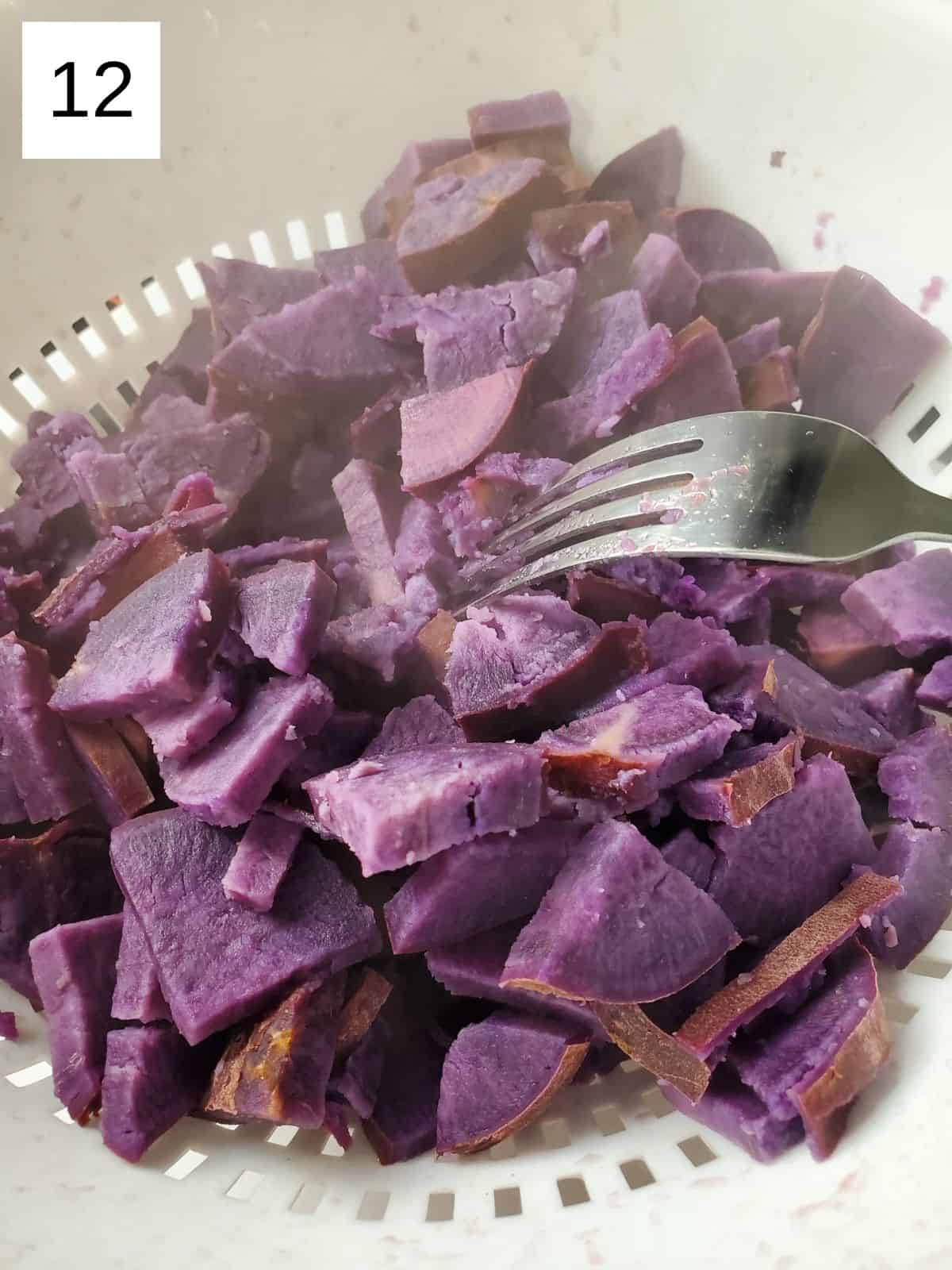 draining the cooked and softened pieces of purple sweet potatoes on a white strainer.