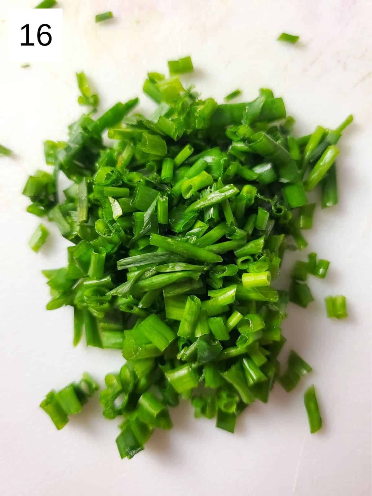 sliced chives on a white chopping board.