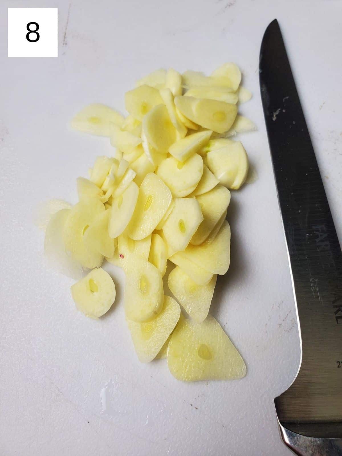 chopped garlic on a white chopping board.