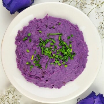 final mashed purple sweet potatoes with chives on a white plate.
