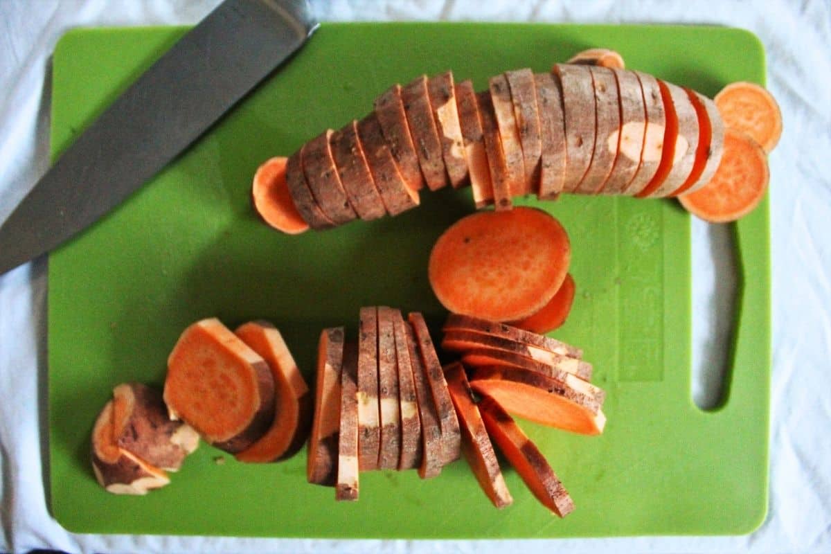 equally sliced sweet potatoes on a green cutting board.