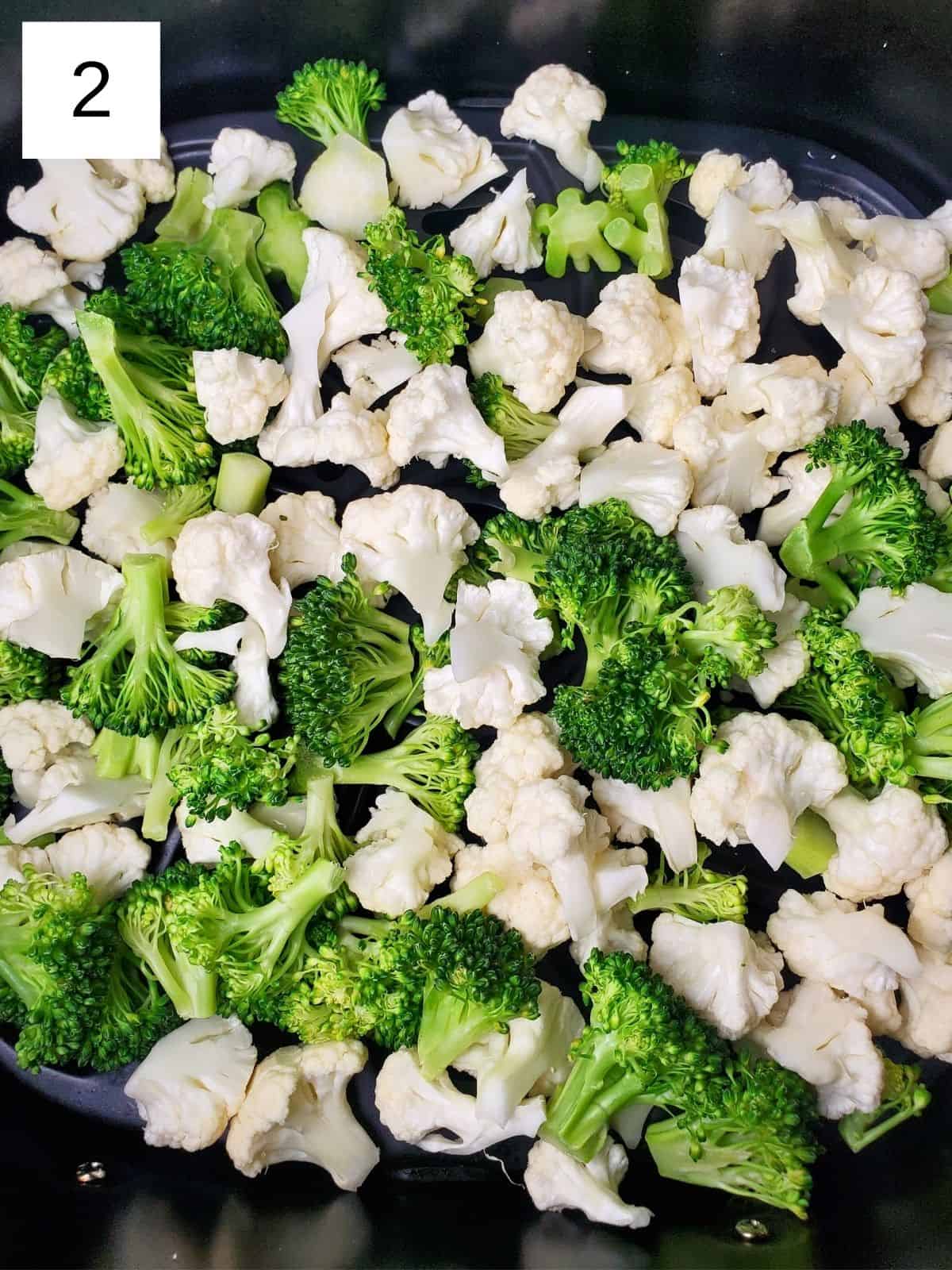fresh broccoli and cauliflower, chopped into small pieces, in an air fryer.