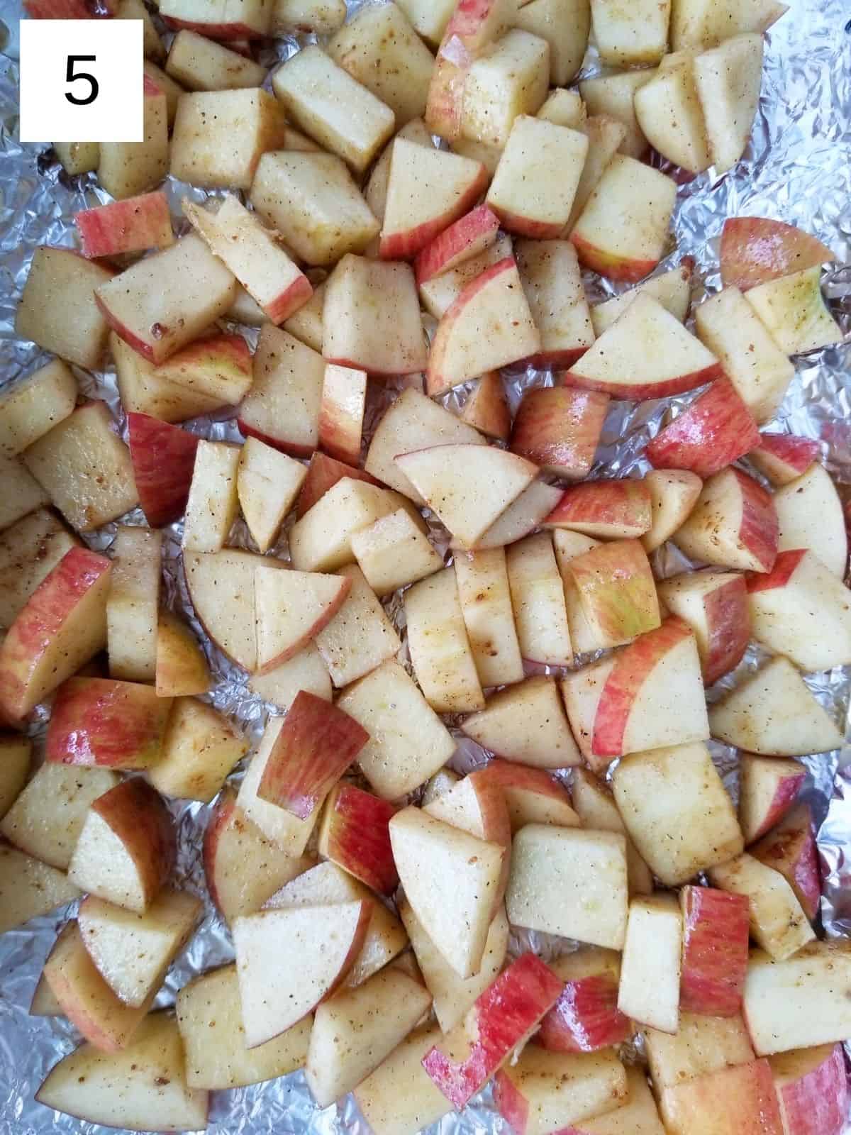 layered apple pieces, coated with a seasoning mixture, on a baking dish lined with foil.