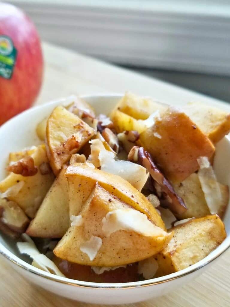 spiced baked apples topped with coconut chips in a bowl.