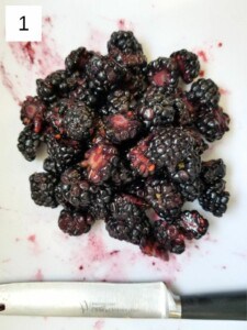 sliced blackberries on a white chopping board.