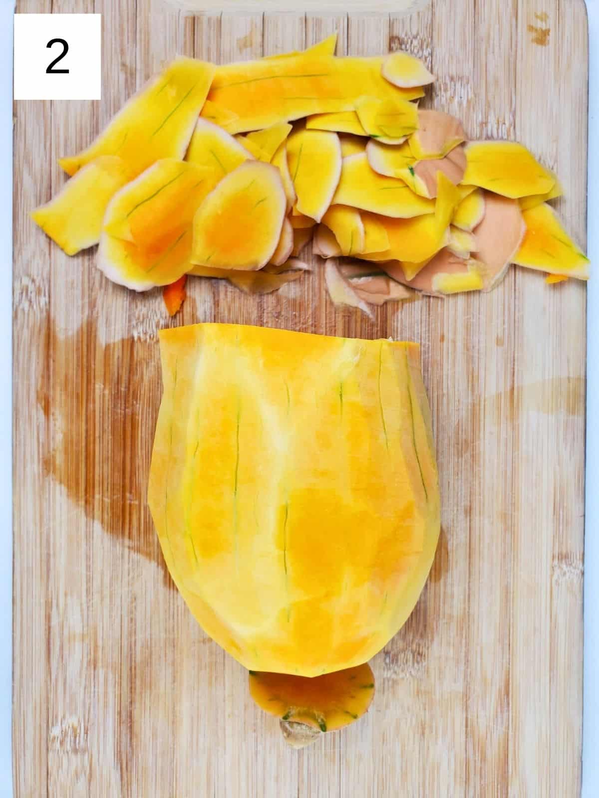 peeled half of butternut squash on a wooden chopping board.