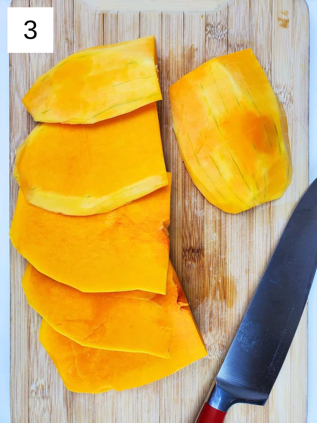 thinly sliced butternut squash on a wooden chopping board.