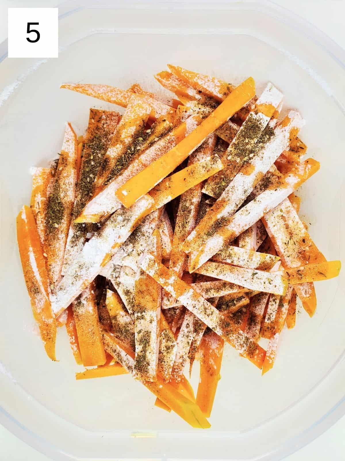 butternut squash slices, topped with seasonings including za'atar, garlic powder, sea salt, tapioca starch, and olive oil, in a bowl.