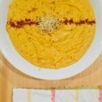 butternut squash tahini soup, topped with hemp seeds, on a plate.