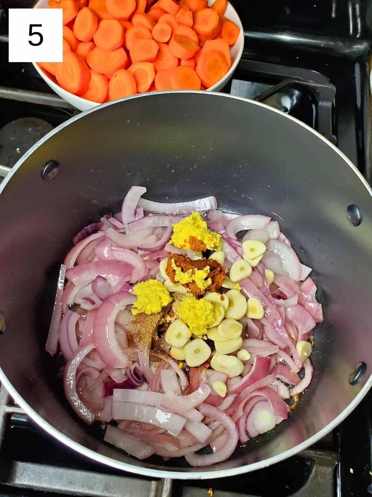 soften chopped onions, and seasonings on top, including garlic, ginger, turmeric, coriander powder, and cumin, in a pot.