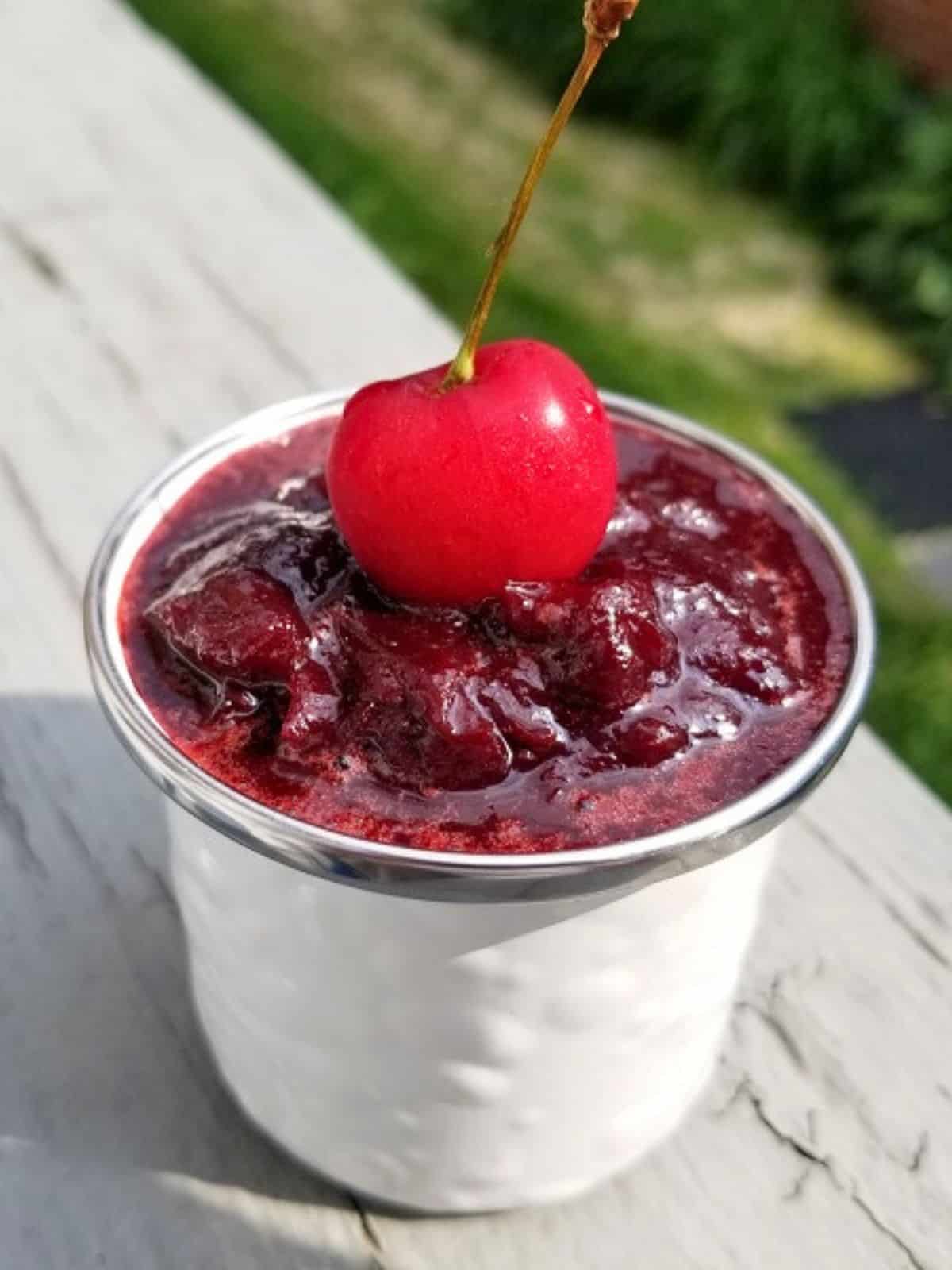 fresh cherry on top of cherry jam in a glass jar.