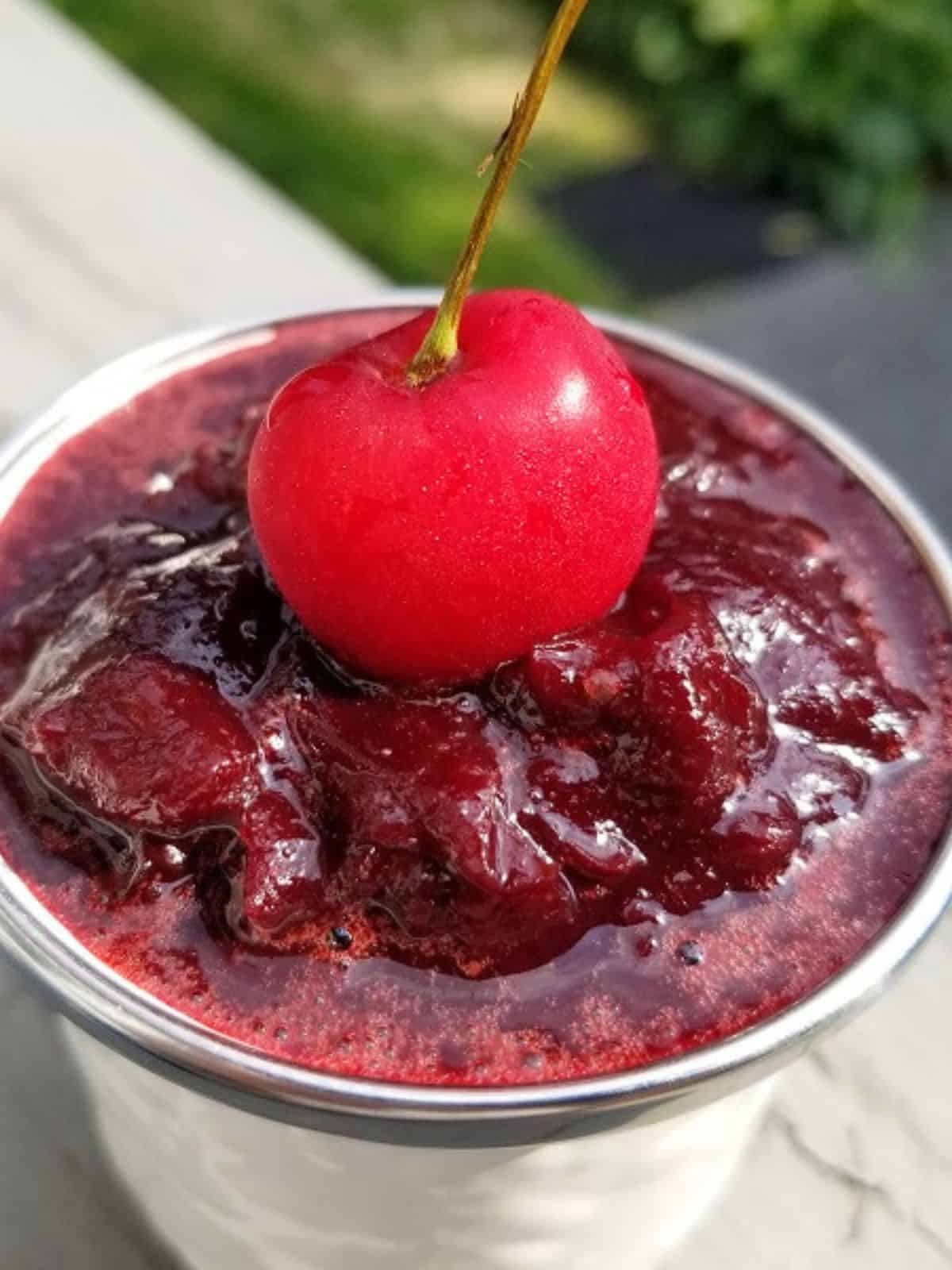 fresh cherry on top of cherry jam in a glass jar.