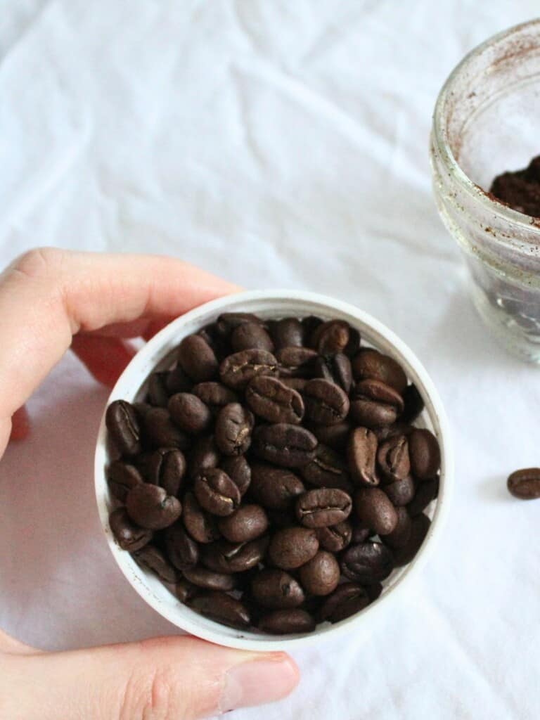ground coffee in a container and some dark-roasted coffee beans.